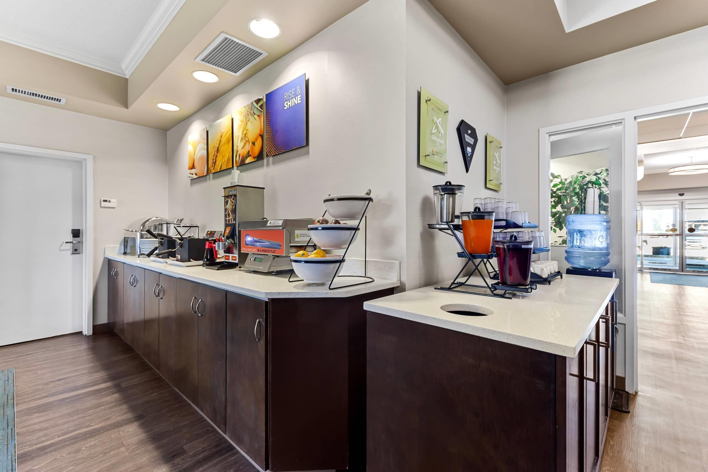 A modern kitchen area with a breakfast bar, coffee station, and a water dispenser.