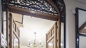 A hotel entrance with a wooden double door, a chandelier, a reception desk, and a small flower arrangement. - INTER Puerta del Sol - Auto Check-in (Madrid)