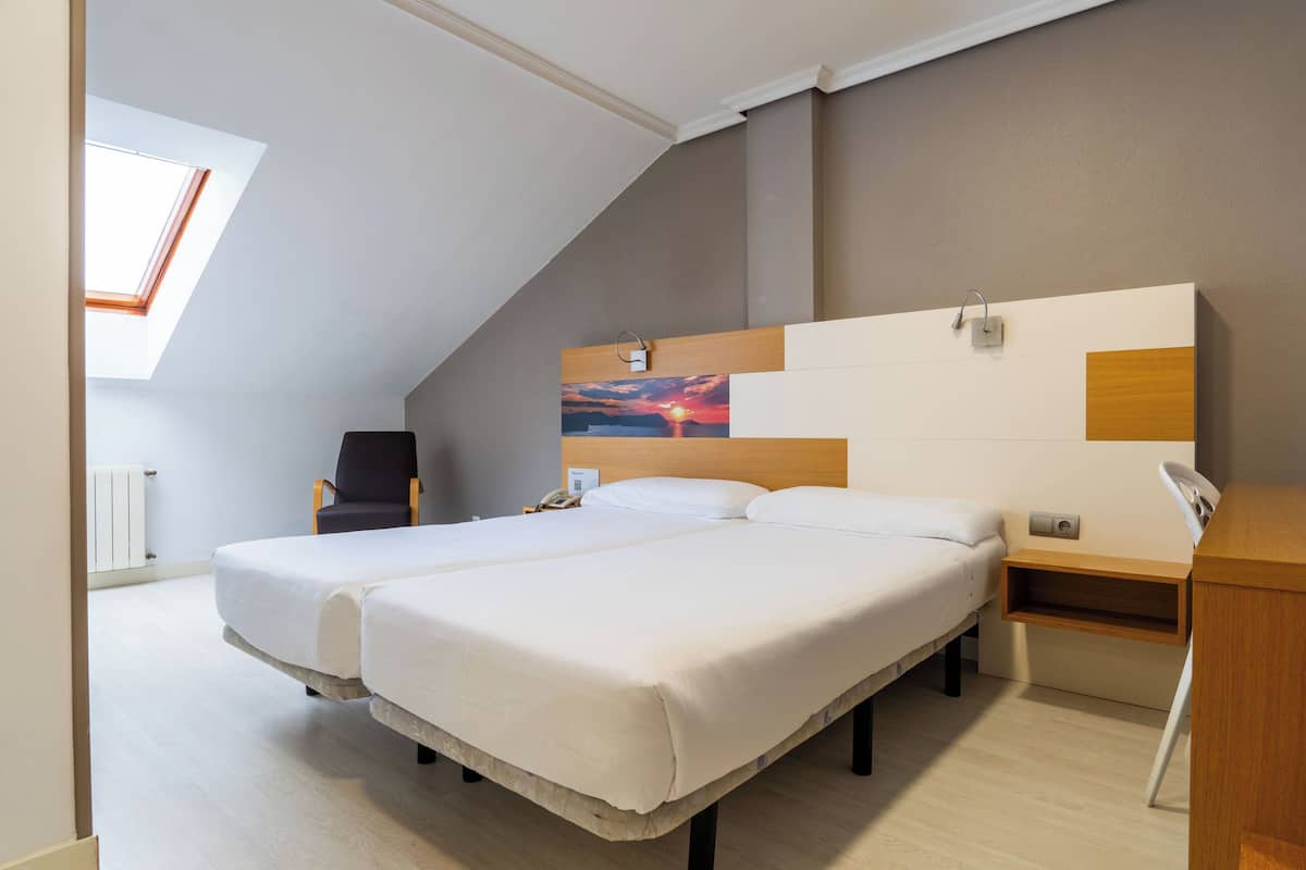 A bedroom with a bed, a chair, a desk, and a painting on the wall.