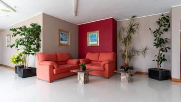 Una sala de estar moderna con un sofá rojo, dos mesas de centro negras y plantas en macetas.
