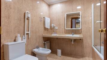 A modern bathroom with a toilet, bidet, sink, and mirror.