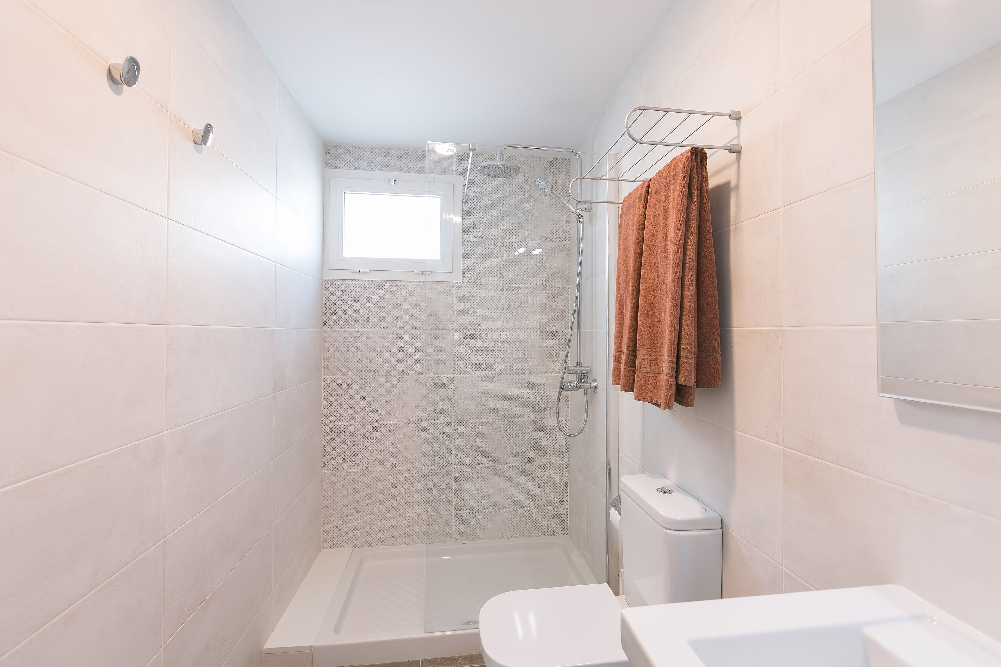 Un baño pequeño y moderno con ducha, inodoro y lavamanos.