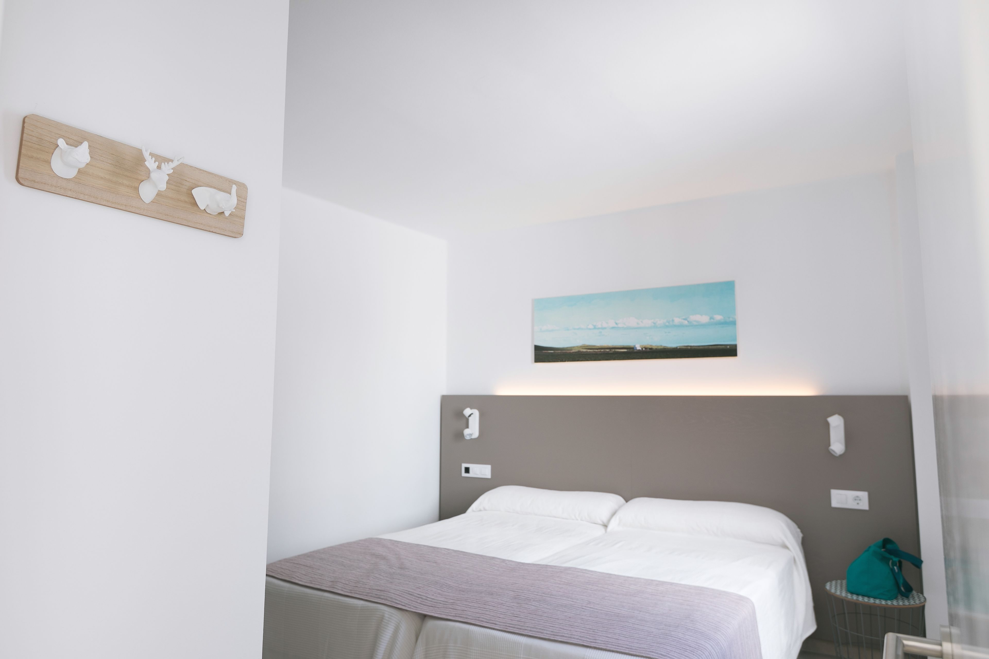 A hotel room with a bed, a wall-mounted picture, and a small table with a bag.