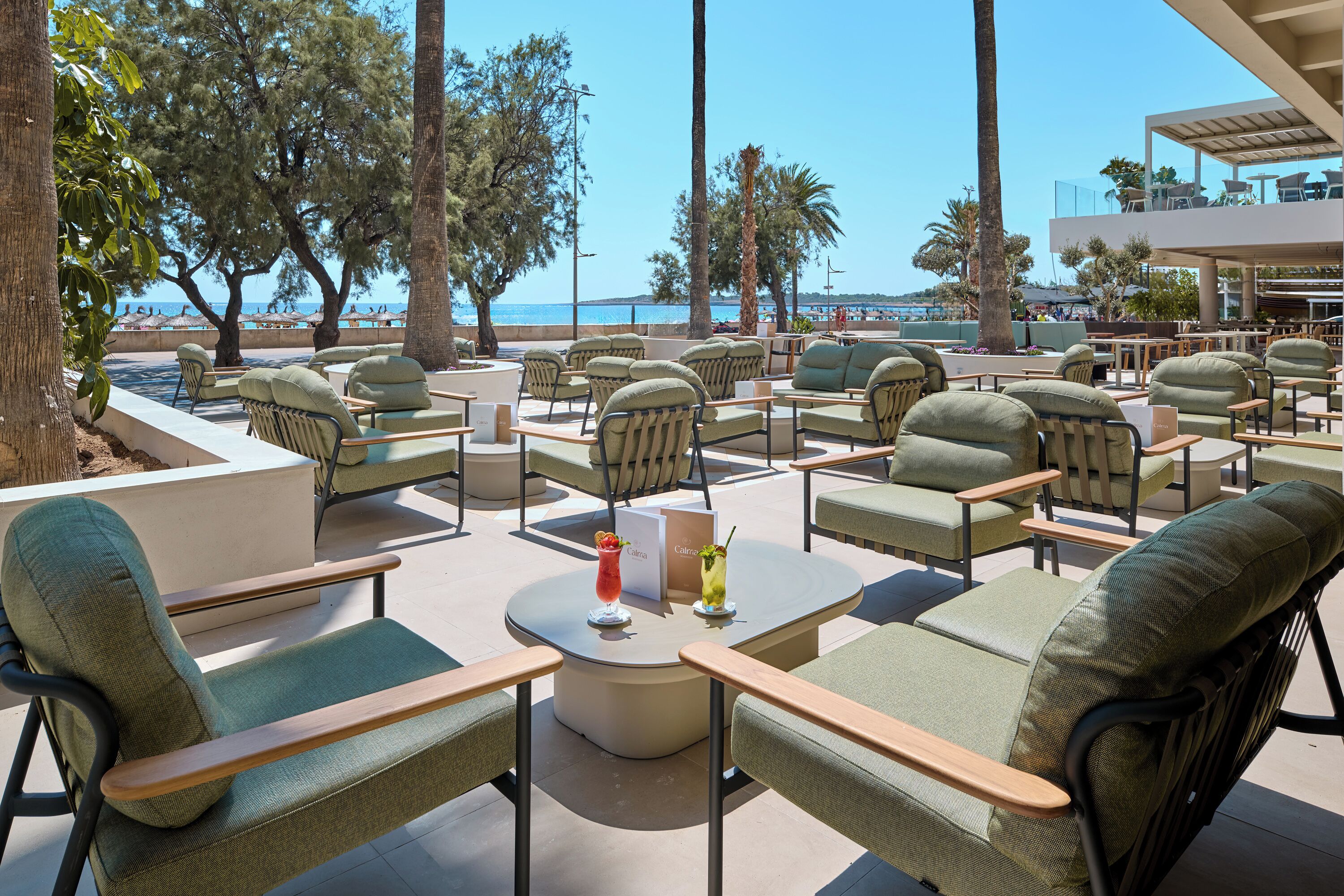 Un espace extérieur aménagé avec des tables et des chaises, offrant une vue sur la plage.