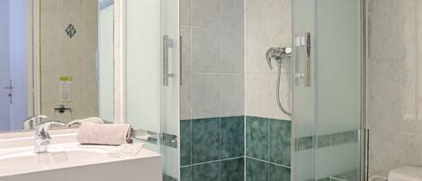 Een moderne badkamer met een glazen douchecabine, een wit wastafelmeubel en een toilet.