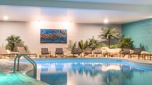 A pool area with lounge chairs, a hot tub, and a painting on the wall.