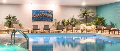 A pool area with lounge chairs, a hot tub, and a painting on the wall.