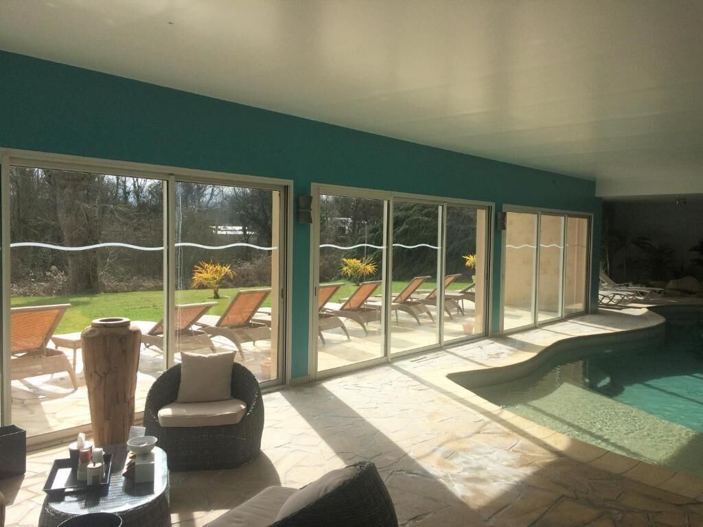 Patio interior soleado con piscina, puertas correderas de vidrio y mobiliario exterior.