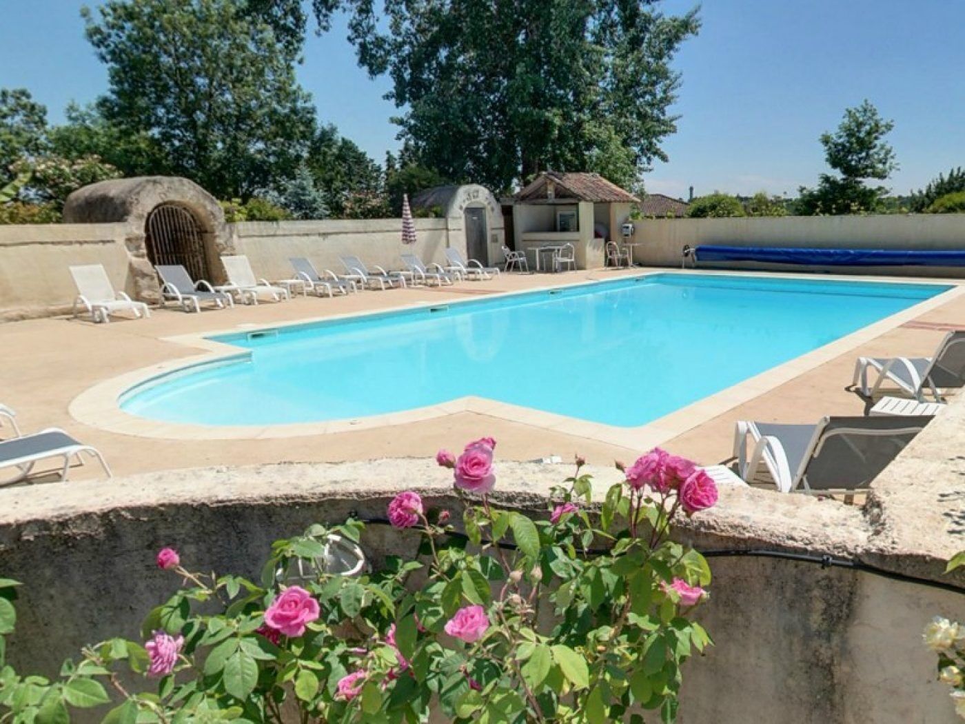 A swimming pool with lounge chairs and a small building in the background.