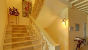 Una escalera con barandilla, un aplique de pared y una mesita con un adorno.