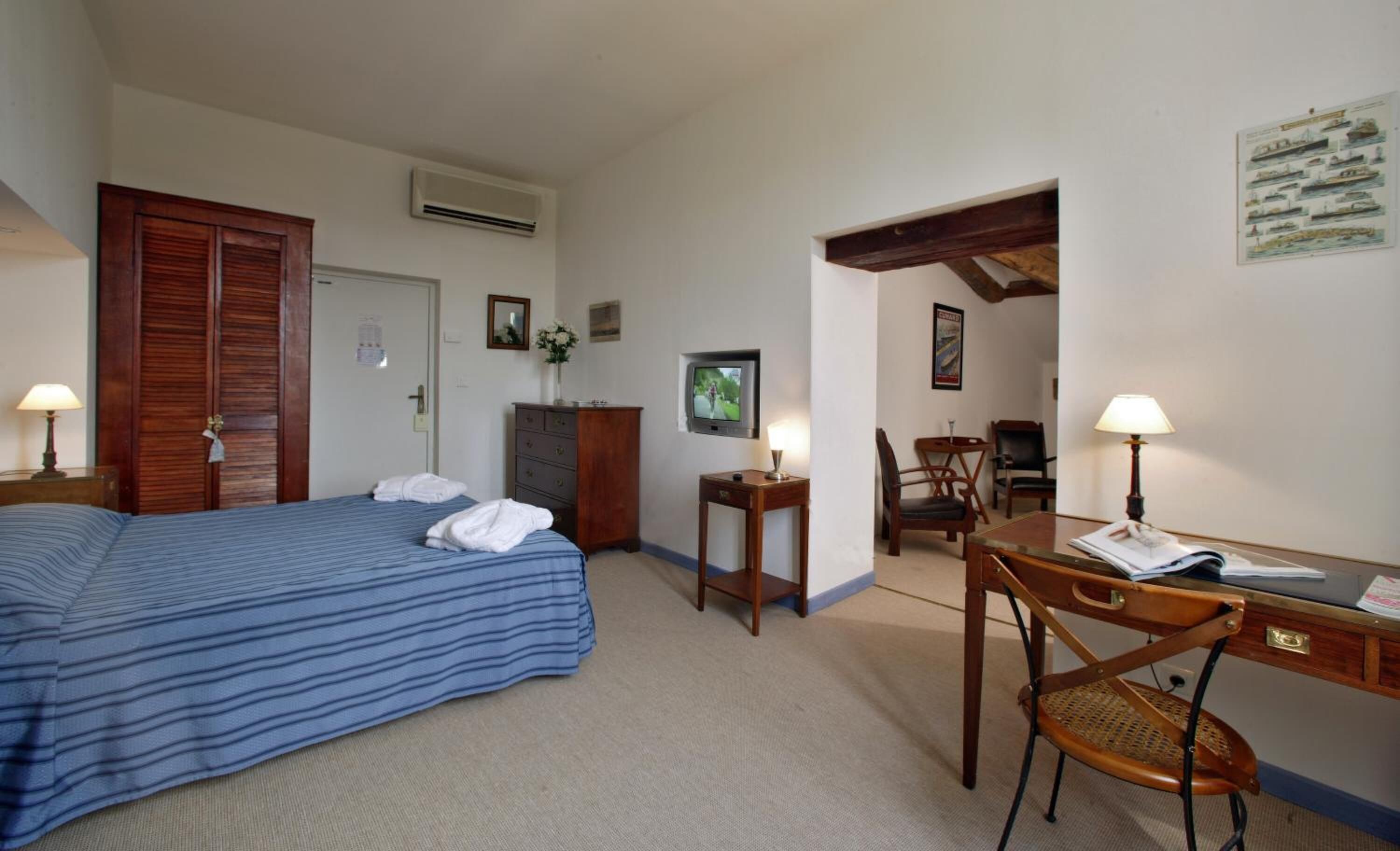 A hotel room with a bed, a desk, a chair, and a TV.