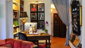 Una sala de estar acogedora con un sillón rojo, un escritorio con una computadora, estanterías y una chimenea.