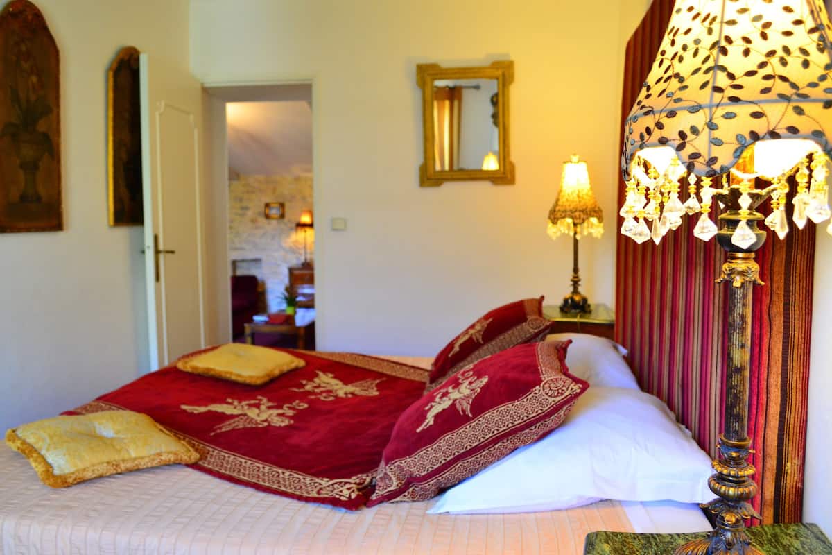 Un lit avec une literie rouge et blanche, une lampe décorative et un miroir au mur.