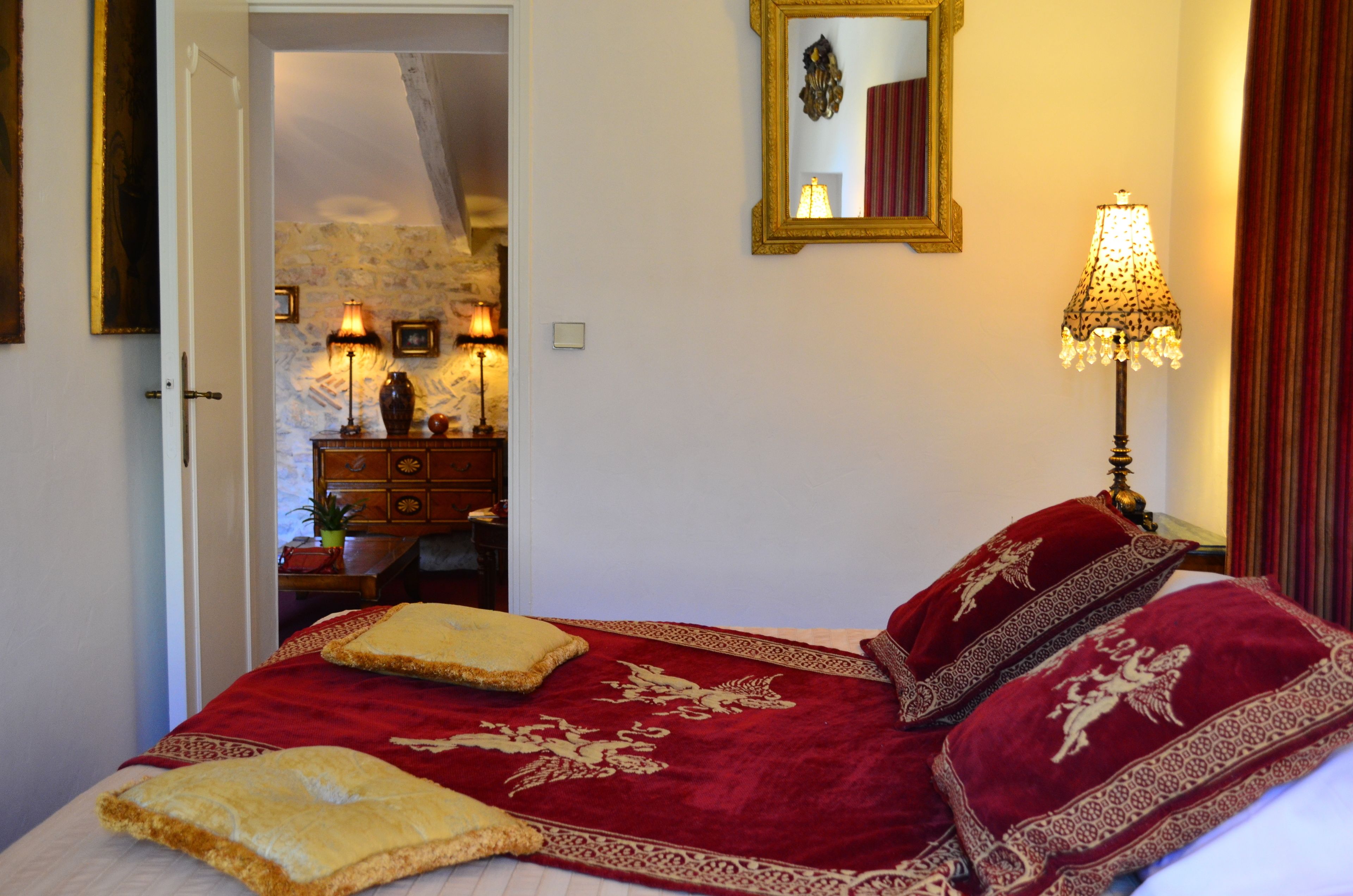 A bedroom with a bed, a lamp, a mirror, and a dresser.