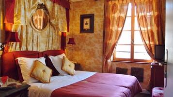 Une chambre d’hôtel avec un grand lit, des rideaux rouges, un miroir et une télévision.