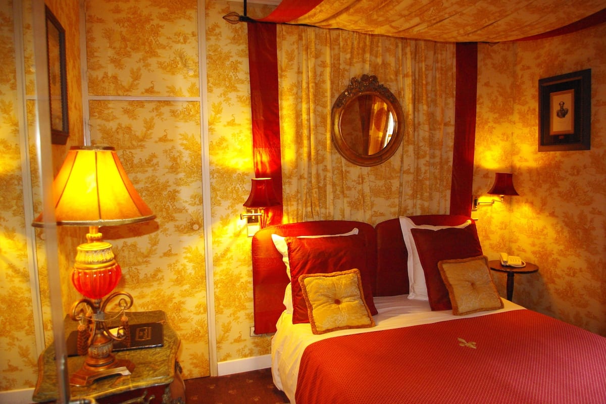 Une chambre d’hôtel avec un lit, deux lampes de chevet, un miroir et une petite table avec un téléphone.
