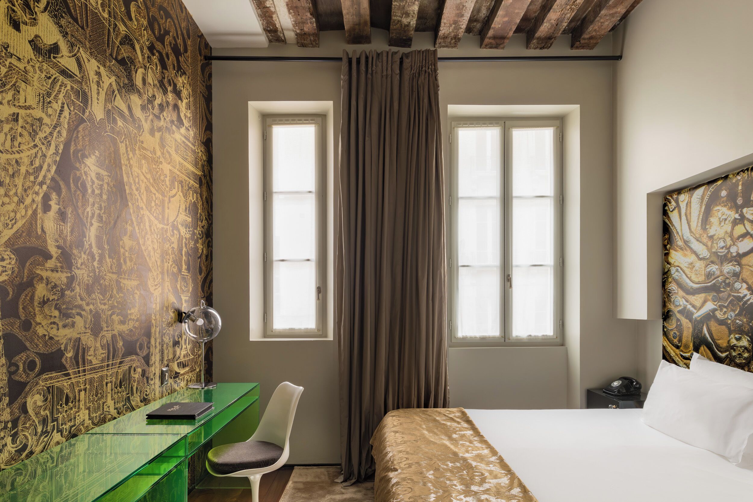 Une chambre à coucher comprenant un lit, un bureau, une chaise et deux fenêtres avec des rideaux.