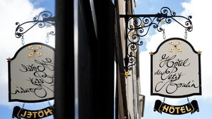 A hotel sign with the name "Hotel du Petit Couran" and a "HOTEL" banner below it. - Hôtel du Petit Moulin, Haute Couture hotel by Lacroix (Paris)