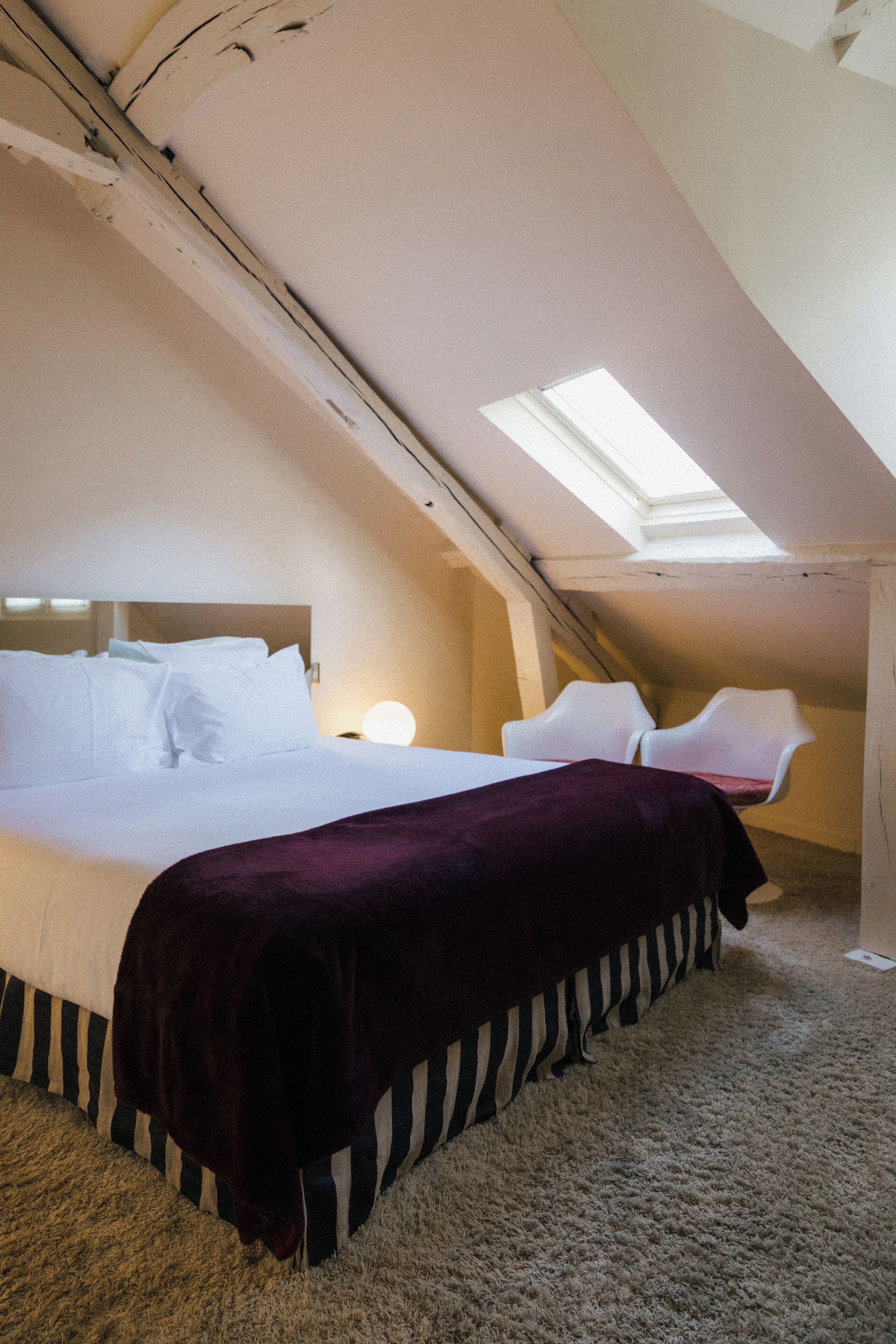 A bedroom with a large bed, a skylight, and a carpeted floor.