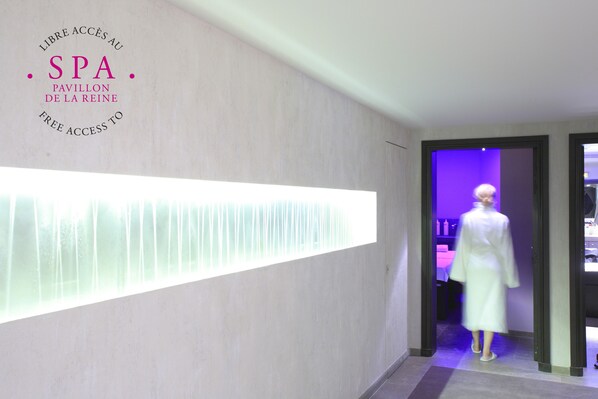 A spa entrance with a mannequin in a white robe, a sign indicating free access, and a modern interior design. - Hôtel du Petit Moulin, Haute Couture hotel by Lacroix (Paris)
