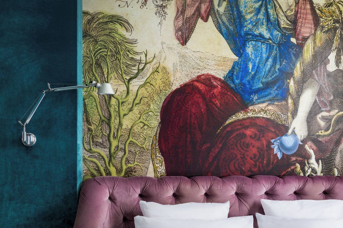 A bedroom with a large mural on the wall, a tufted headboard, and a modern floor lamp.