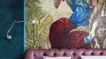 A bedroom with a large mural, a tufted headboard, and a modern lamp.