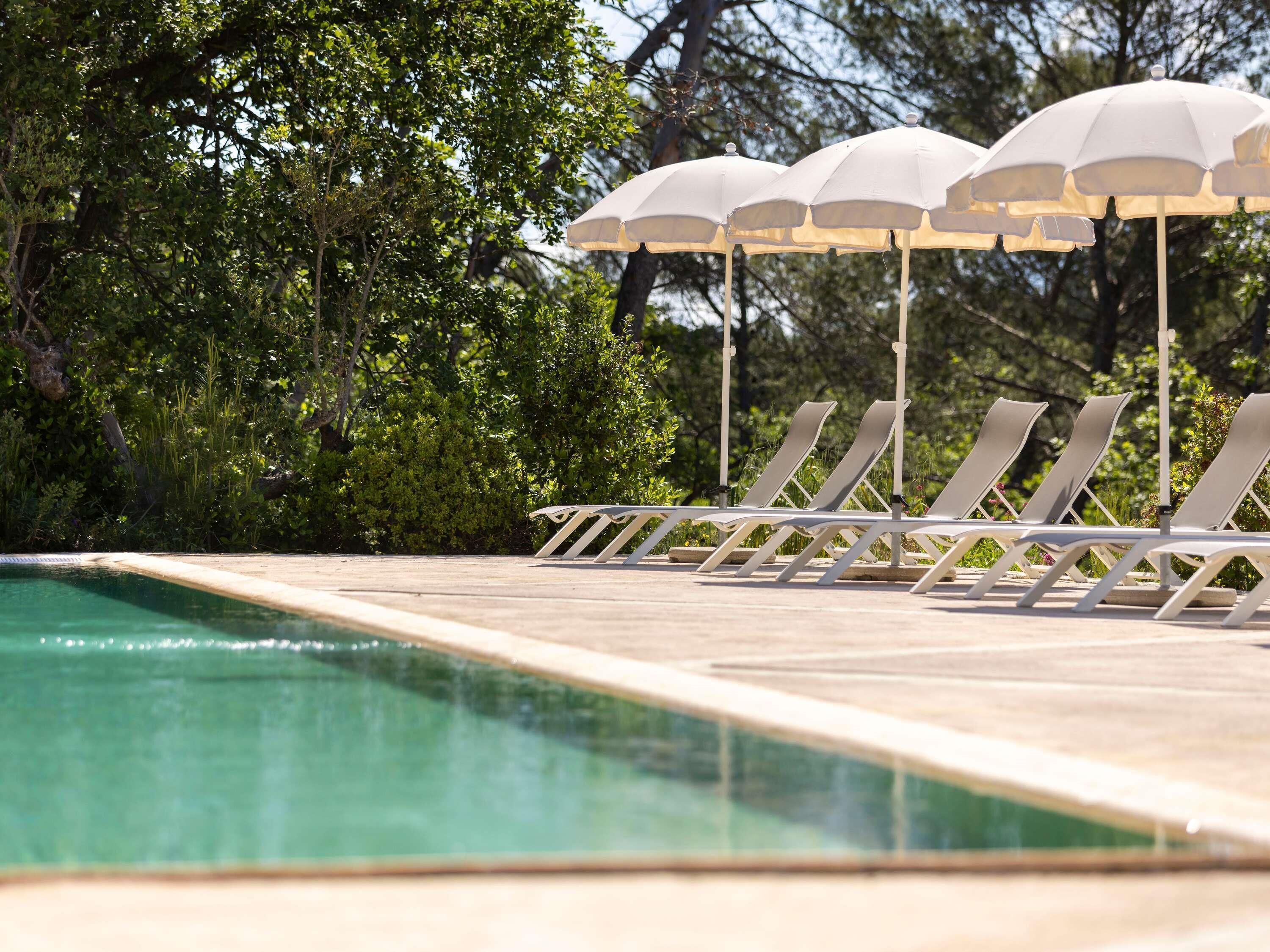 Un área junto a la piscina con sillones de playa y sombrillas.
