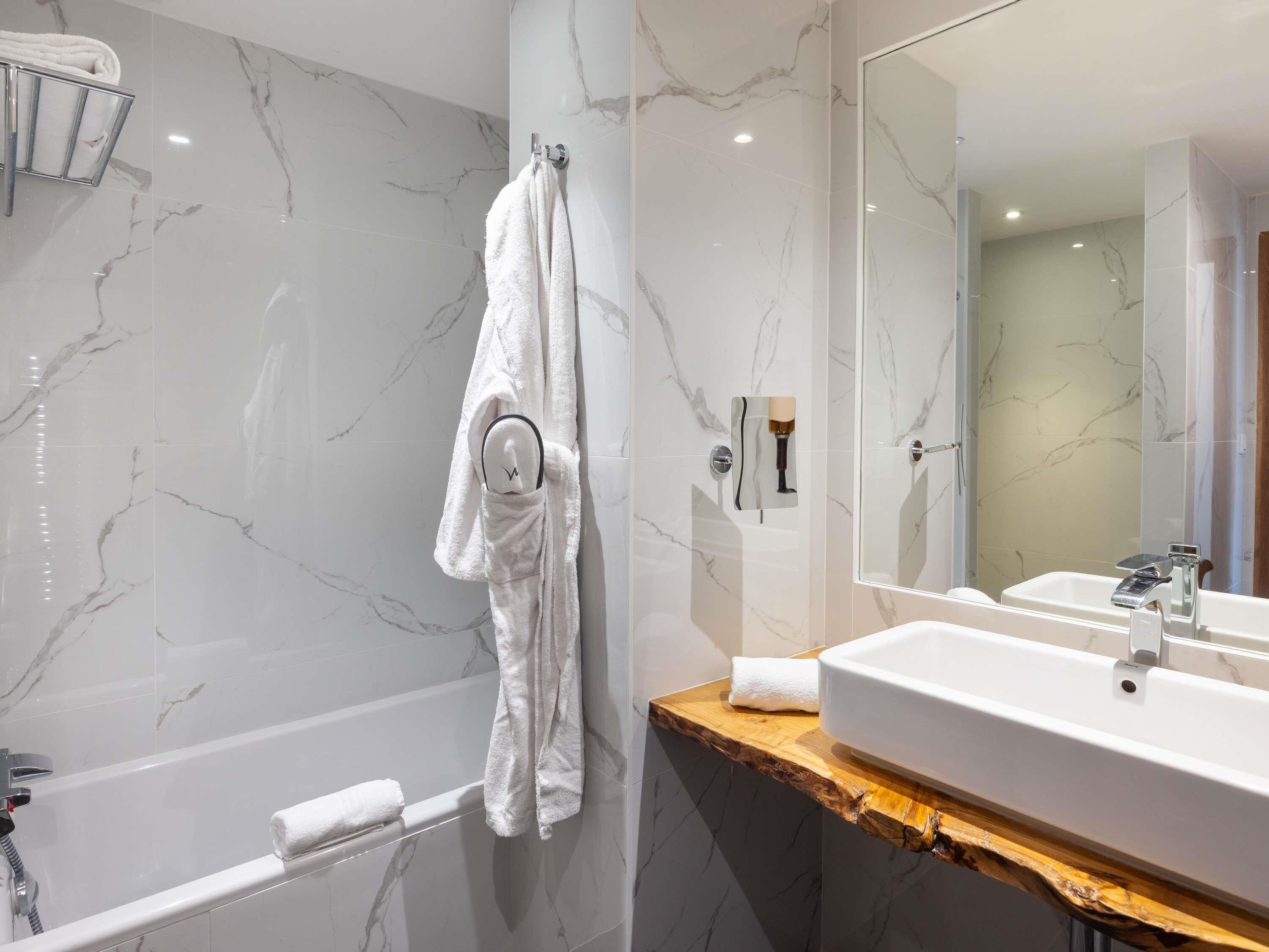 A bathroom with a bathtub, a sink, and a mirror.