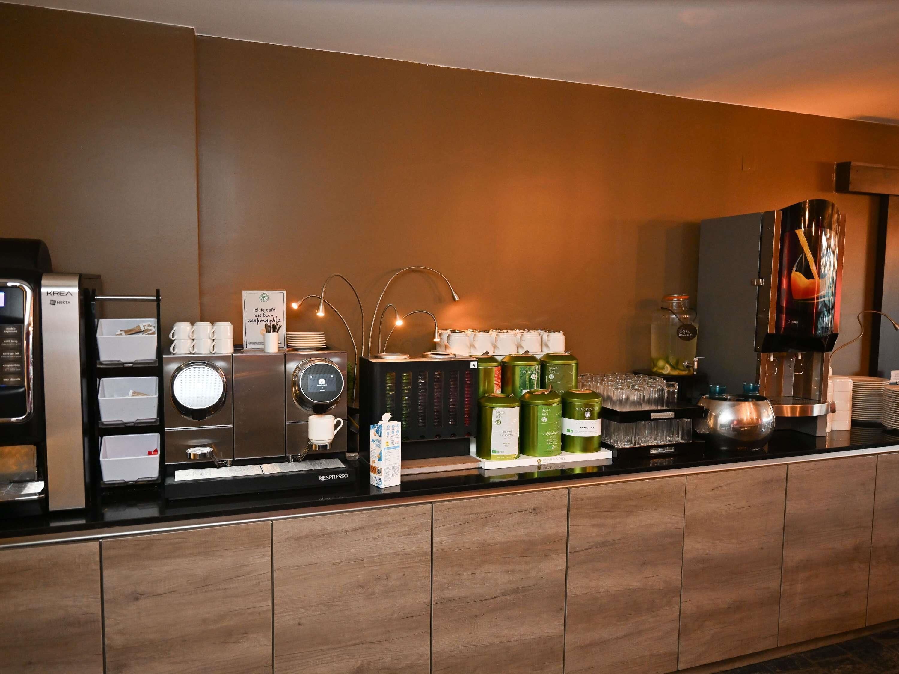 A coffee station with a Nespresso machine, a Krea Nectar dispenser, and various coffee pods and cups.