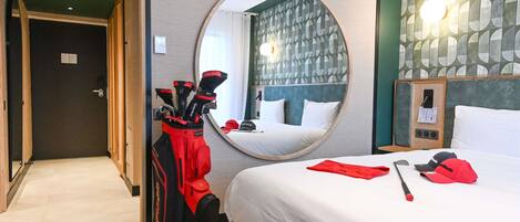 Una habitación de hotel con una cama, un espejo, un bolso de golf y una pared con un diseño geométrico.