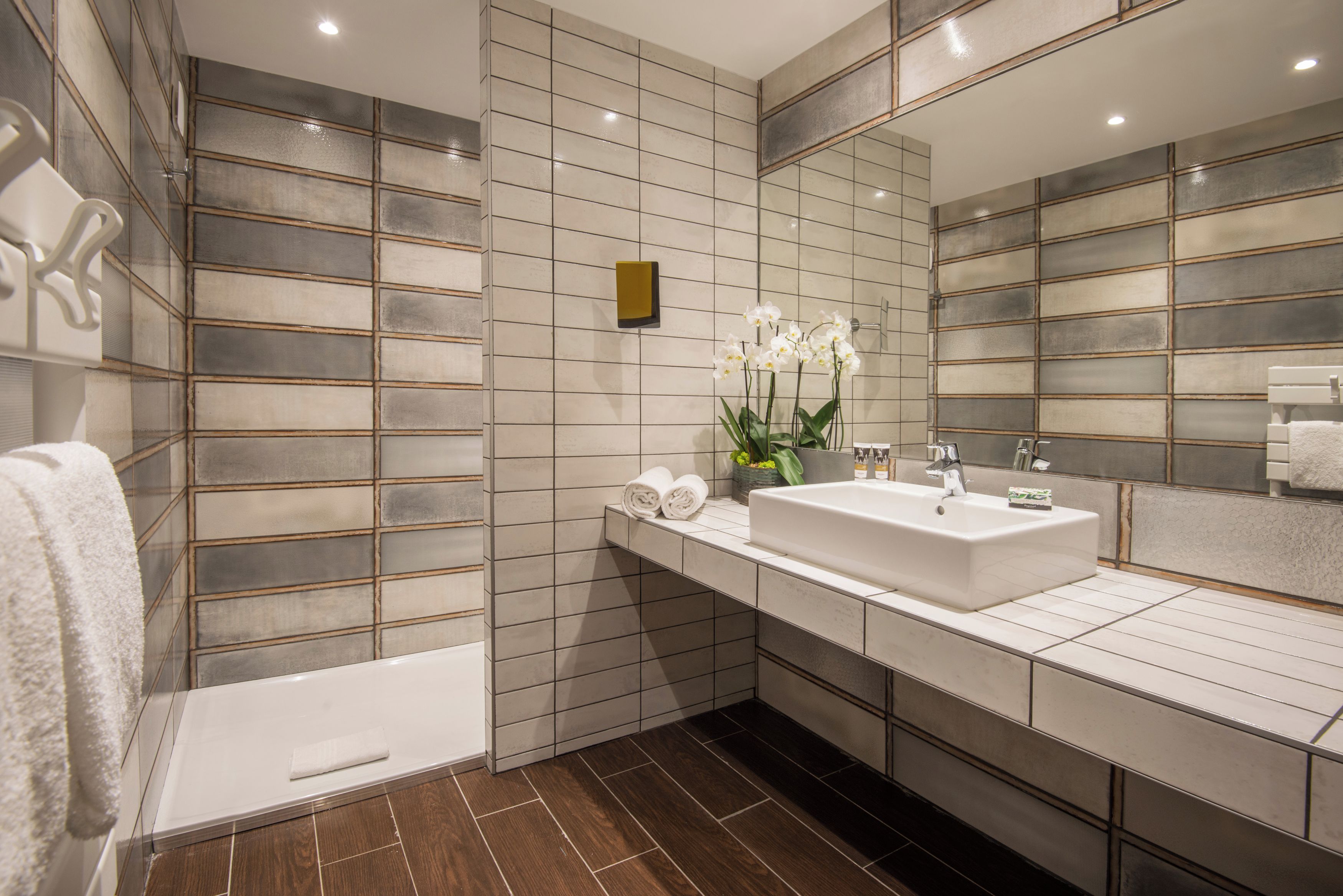Un baño moderno con un espejo grande, lavamanos blanco y una bañera.