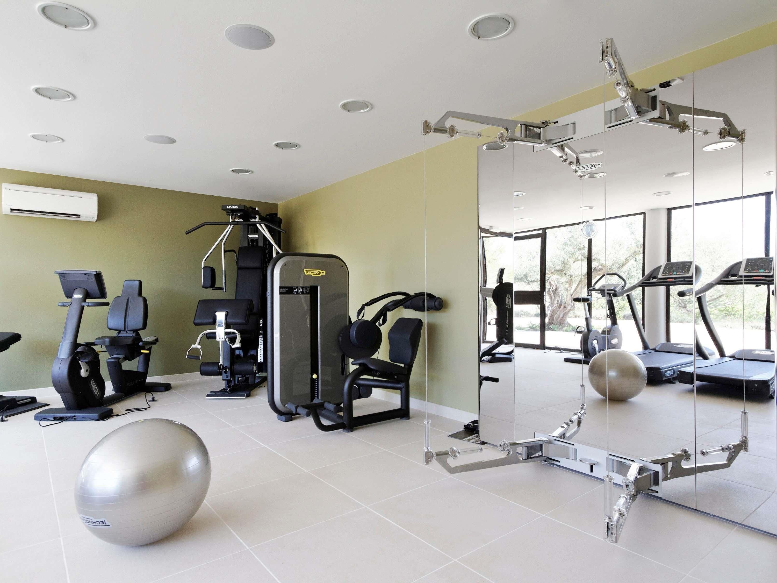 A gym with exercise equipment, a large mirror, and a view of the outdoors.