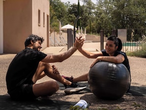Guests can exercise outdoors in a paved area surrounded by trees and a nearby building.