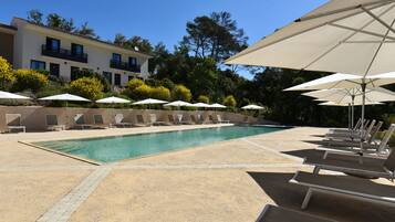 Relax by the resort pool surrounded by lounge chairs and umbrellas.