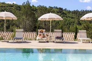 Una piscina al aire libre, sombrillas, tumbonas