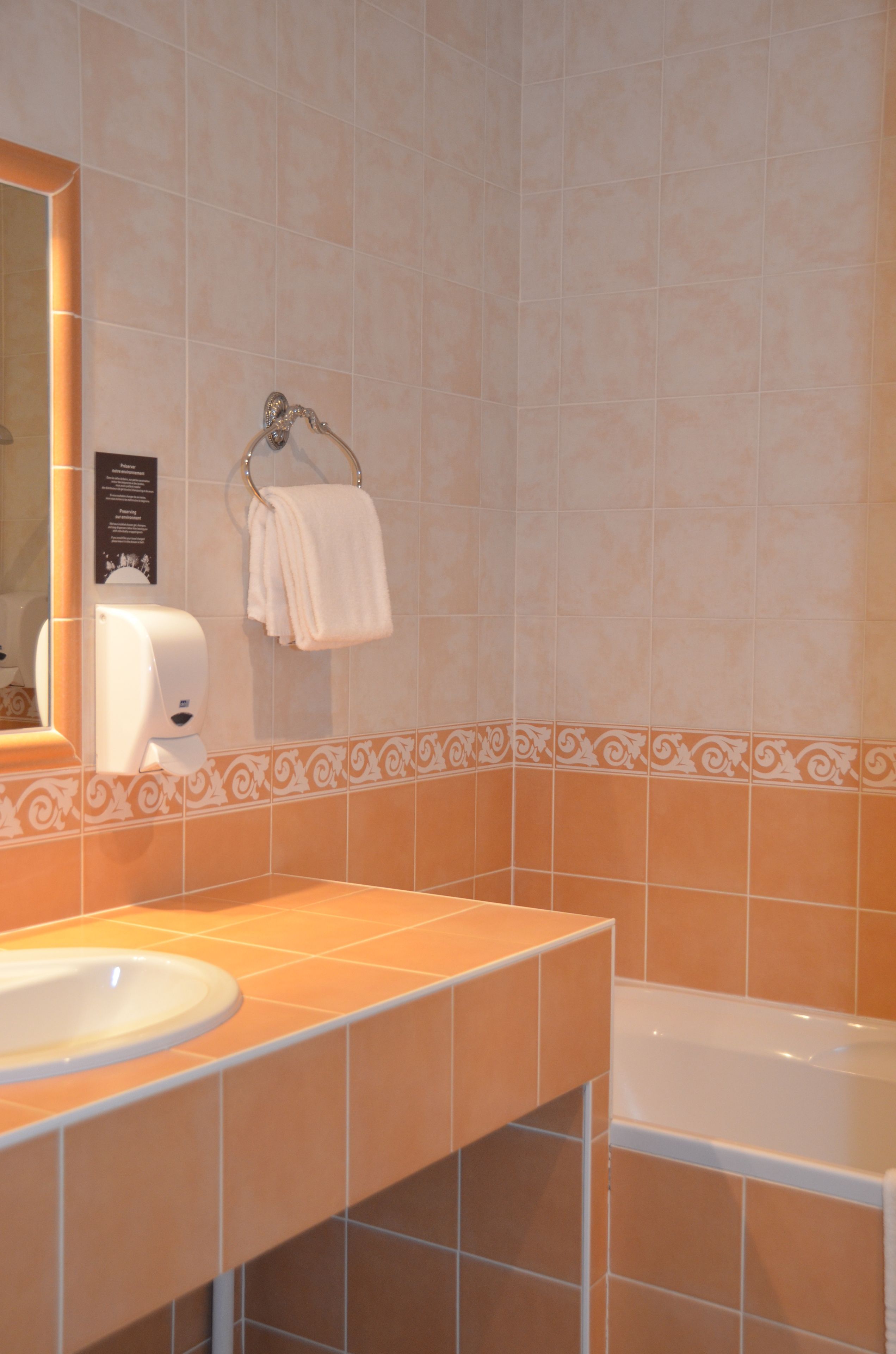 A bathroom with a sink, mirror, towel rack, and a bathtub.