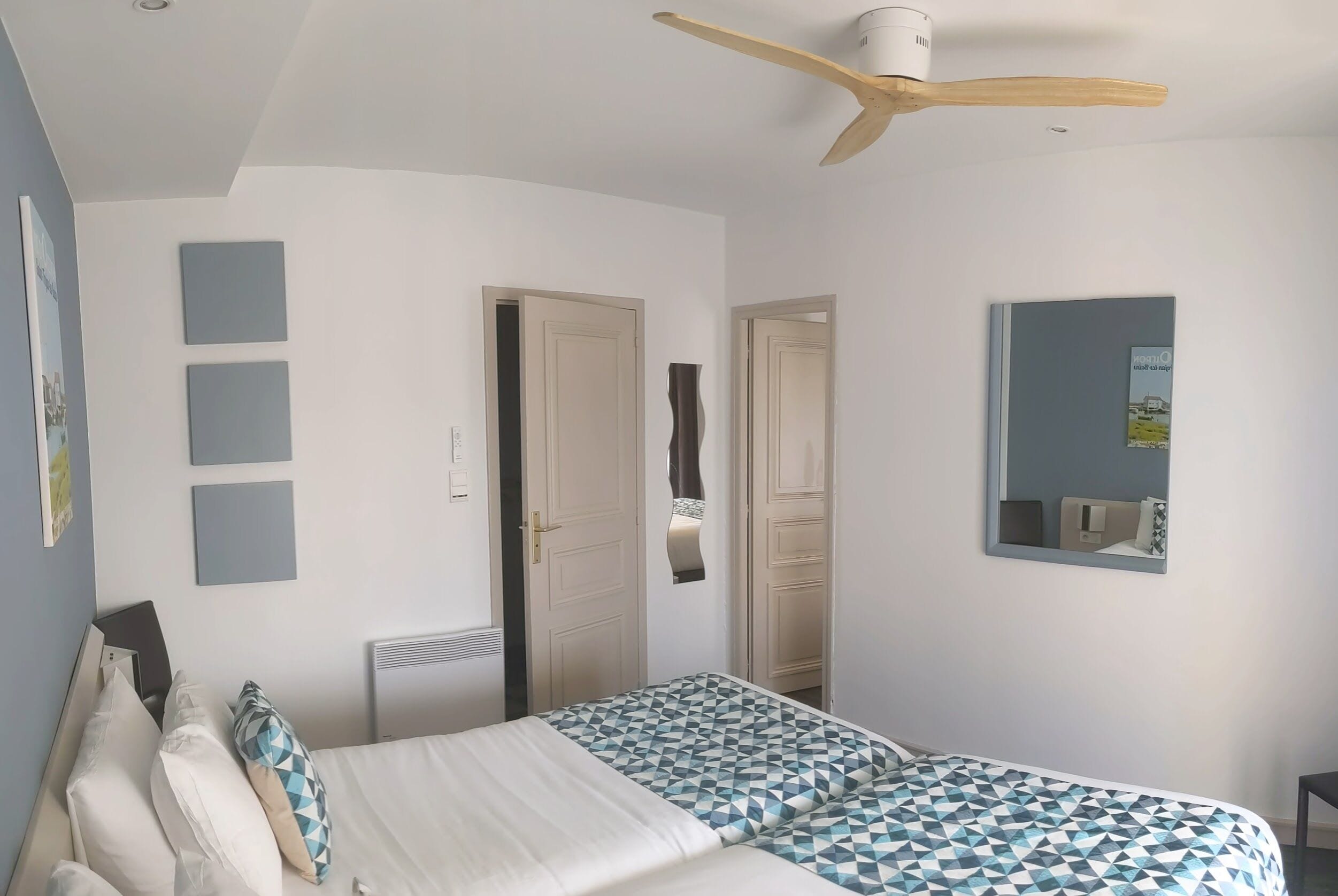 A bedroom with a bed, a ceiling fan, a wardrobe, and a mirror.