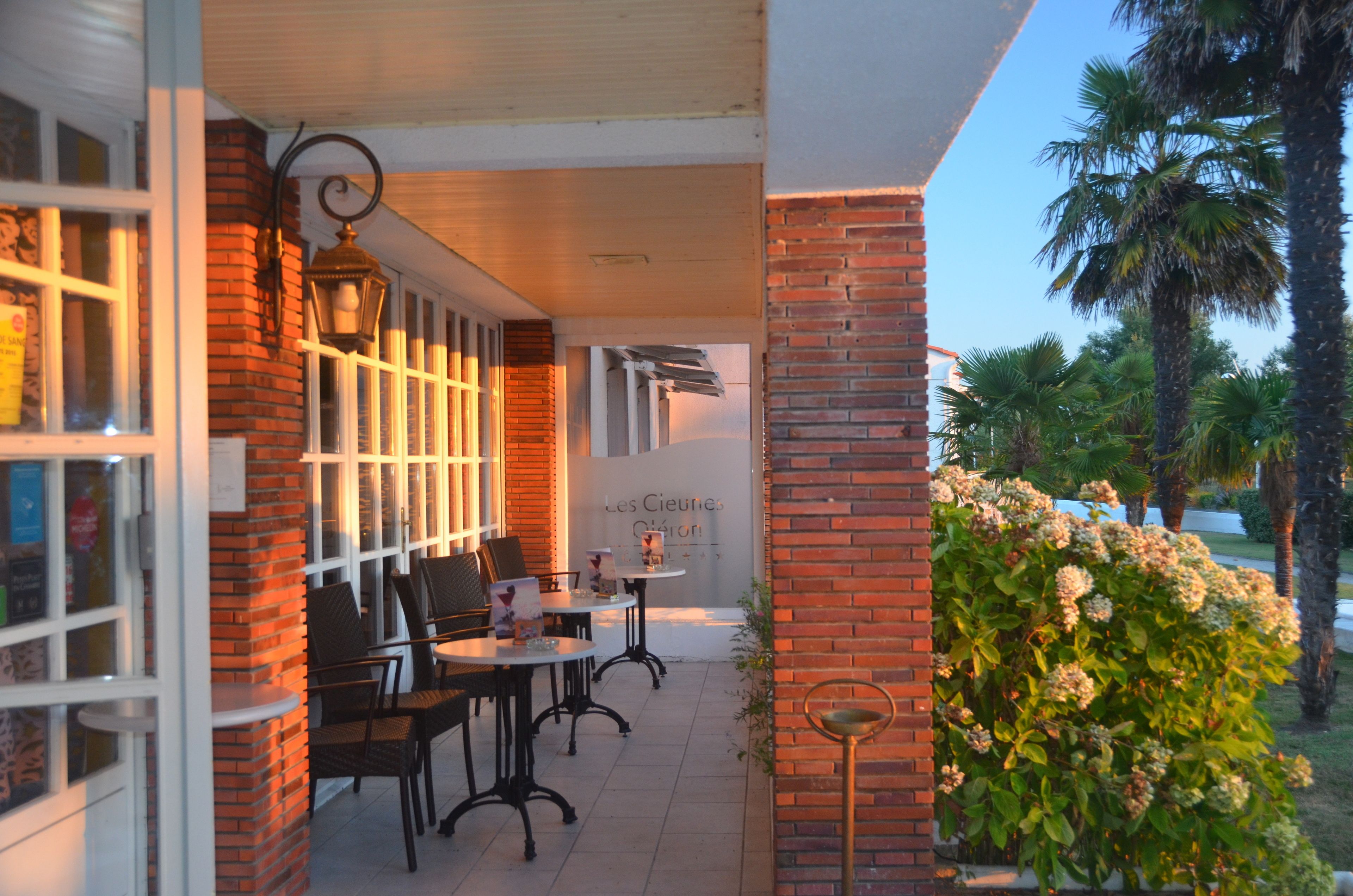 An outdoor cafe area with brick walls, white-framed windows, and tables with chairs.