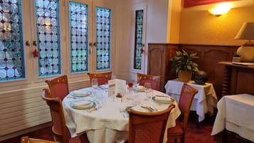 Een eetkamer met een ronde tafel voor vier personen, omringd door houten stoelen met rode kussens.