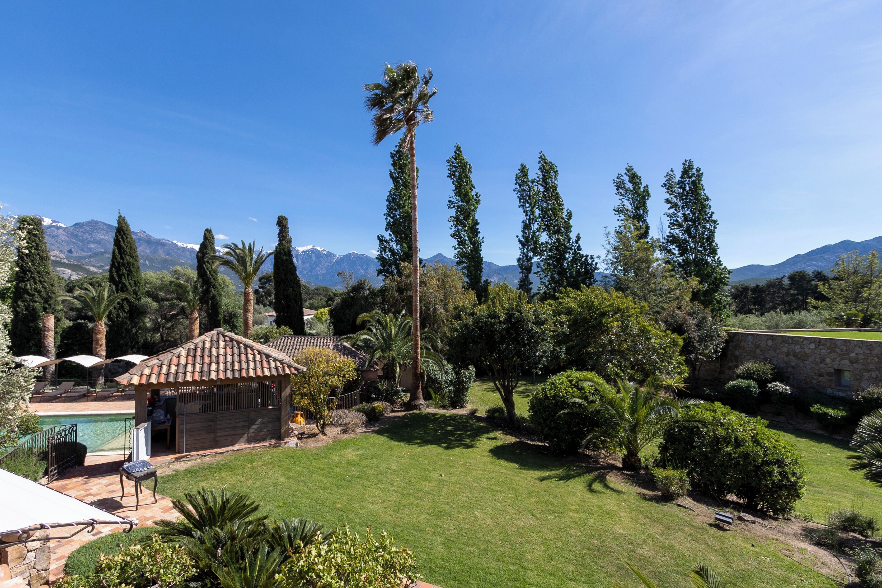 A villa with a swimming pool, a covered patio, and a view of mountains.