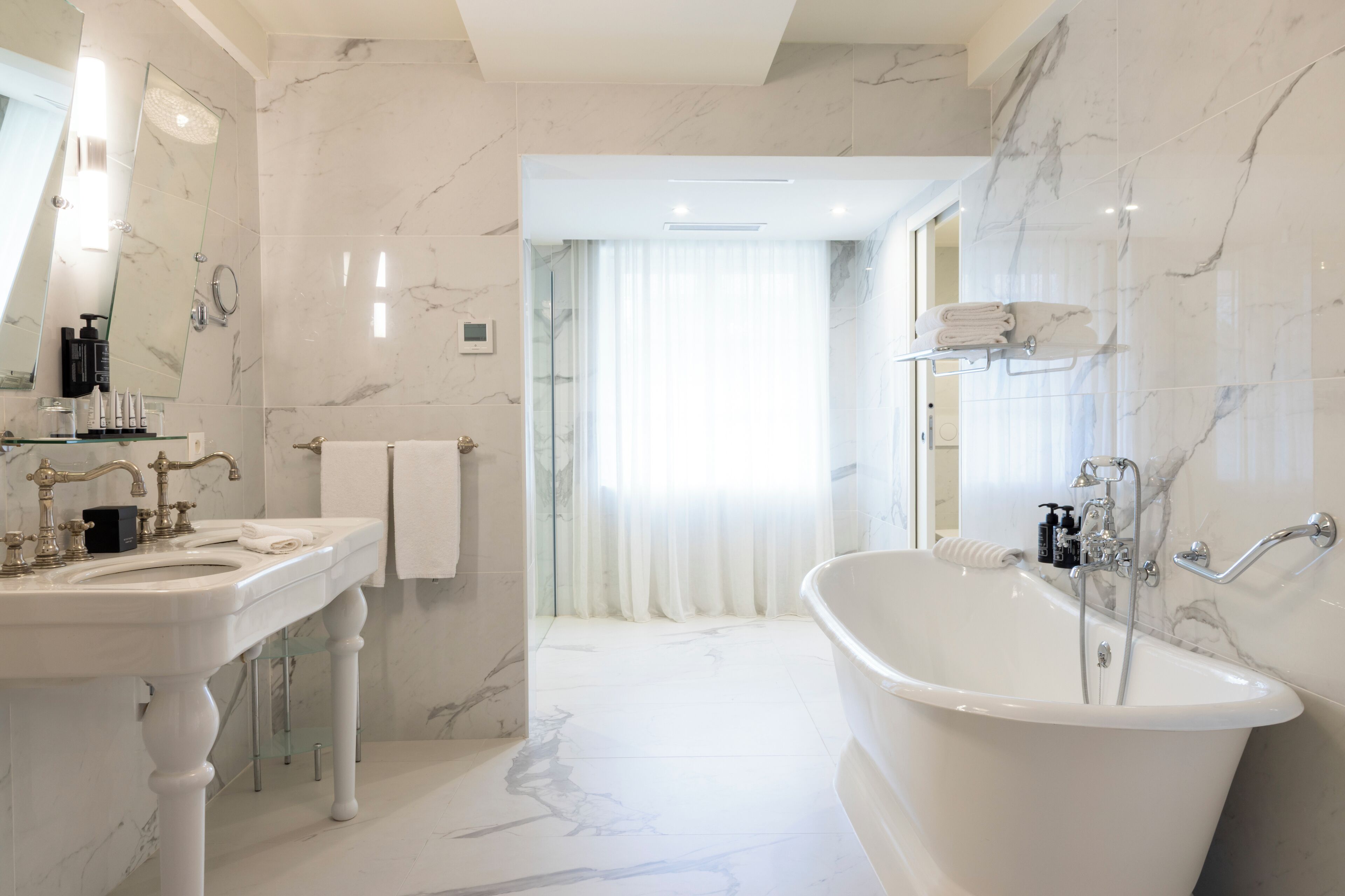 Une salle de bain moderne avec une baignoire sur pieds, un meuble-lavabo avec un miroir et un revêtement de sol en marbre.
