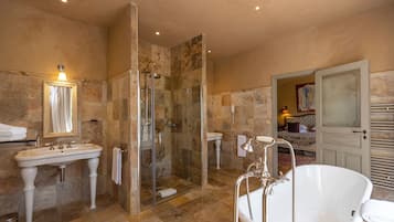 Un baño con ducha de vidrio, bañera independiente y dos lavamanos.
