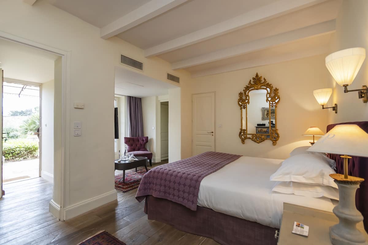 Habitación de hotel con cama, tocador con espejo, lámpara y silla.