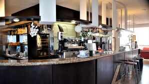 Zona de bar moderna con encimera de granito, taburetes y una variedad de botellas y vasos.