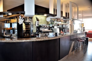 Zona de bar moderna con encimera de granito, taburetes y una variedad de botellas y vasos.