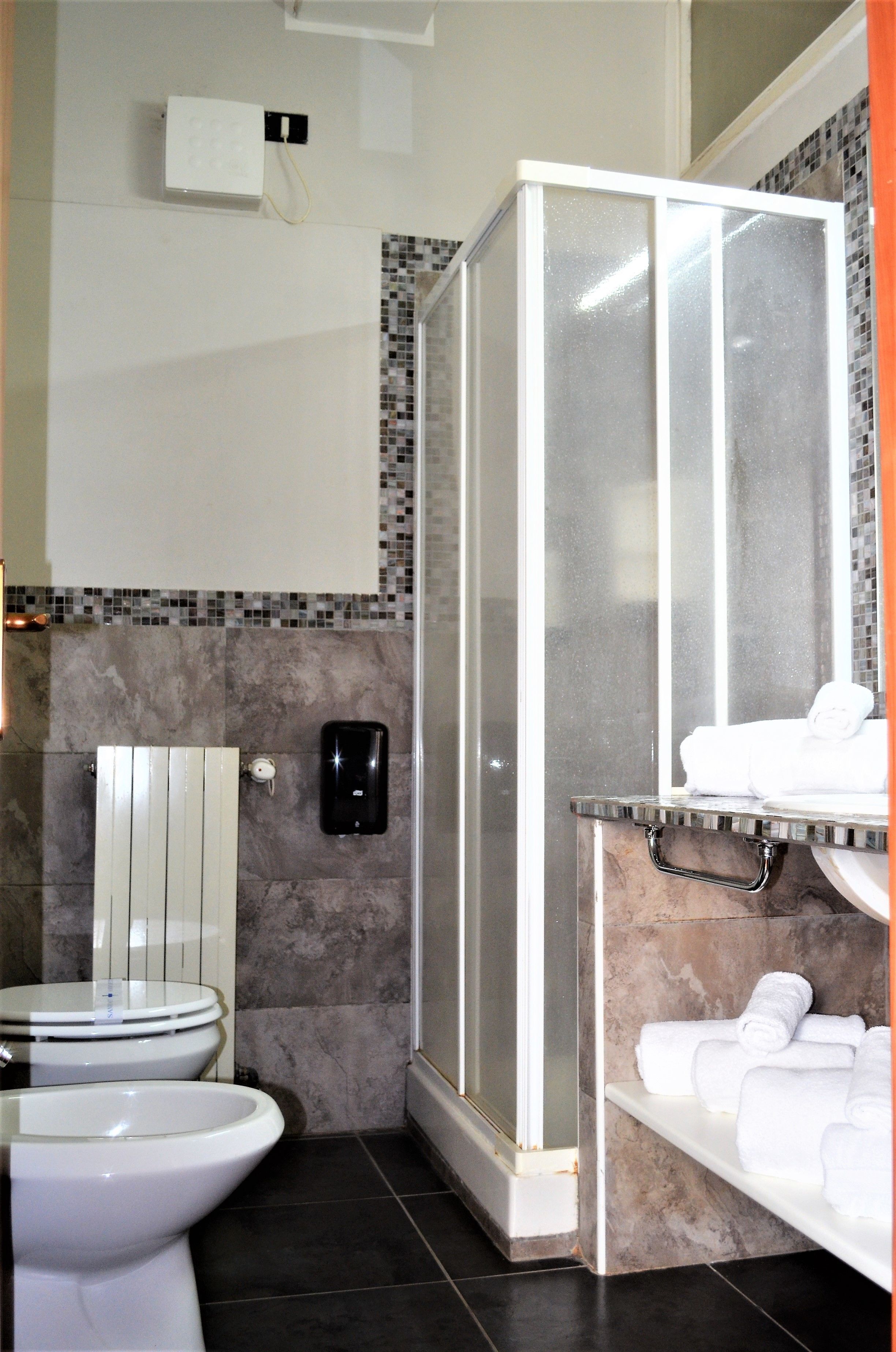 A bathroom with a toilet, a shower enclosure, and a towel rack with towels.