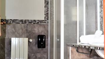 A bathroom with a toilet, a shower enclosure, and a towel rack with towels.