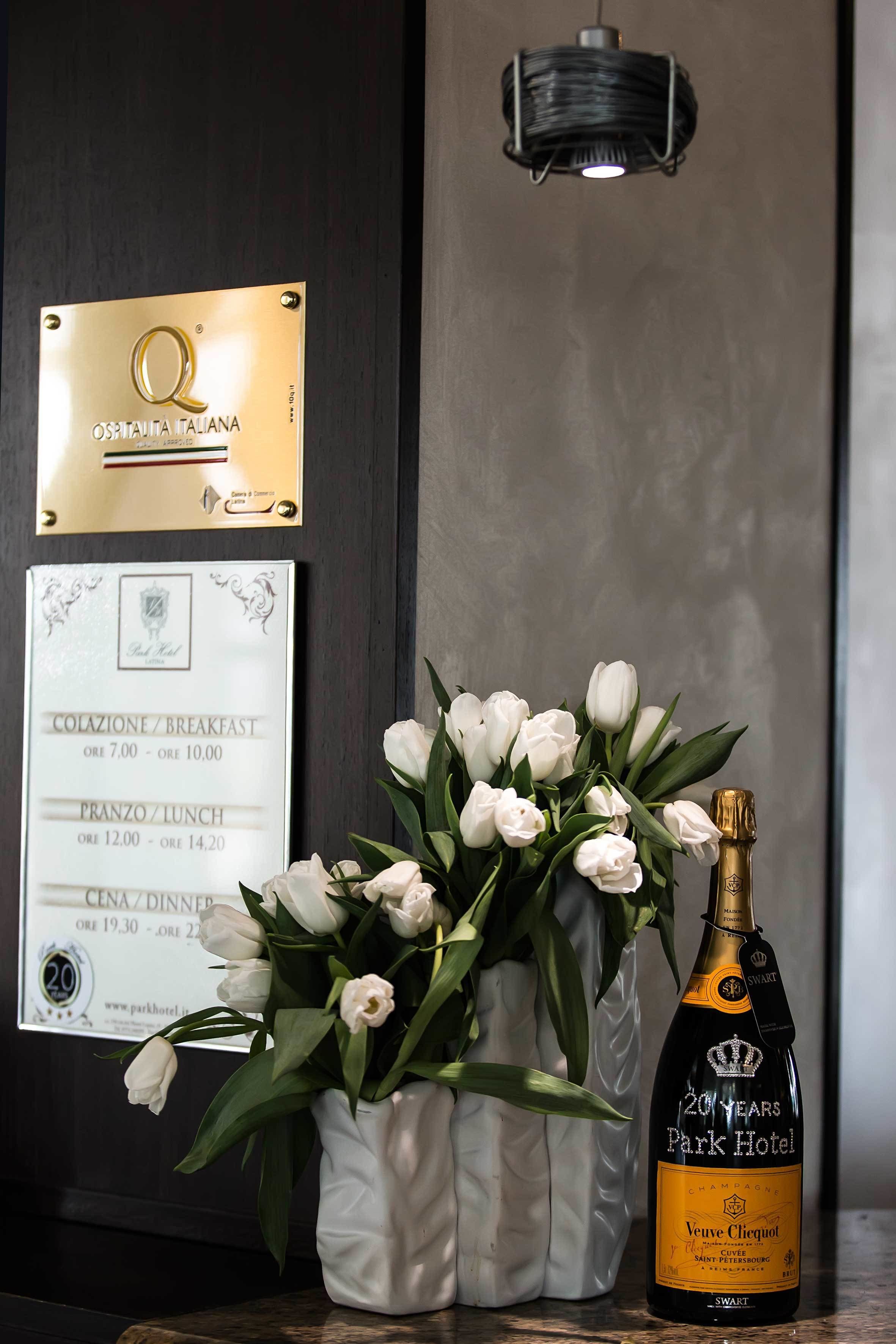 Una placa, un menú, un jarrón con flores blancas y una botella de champán Veuve Clicquot.