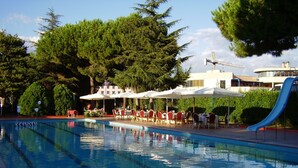 Una piscina con asientos al aire libre cerca y un tobogán.