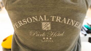 Eine graue Kapuzenjacke mit dem Aufdruck 'PERSONAL TRAINER Park Hotel LATINA' auf dem Rücken.